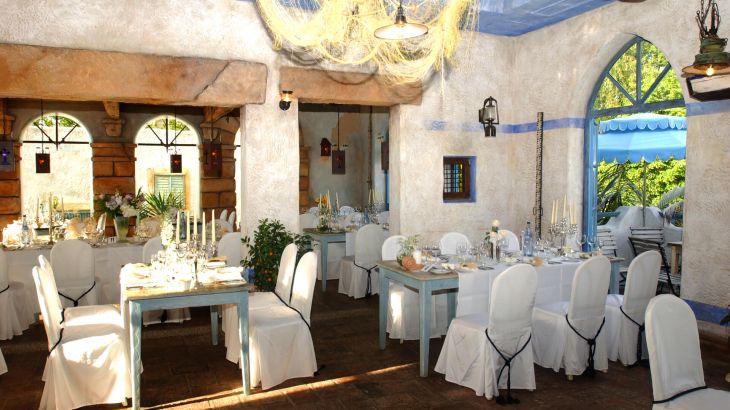 Der für eine Hochzeit geschmückte Innenraum mit weißen Stuhlhussen und Kerzen verschönerte Innenraum der Taverna Mykonos